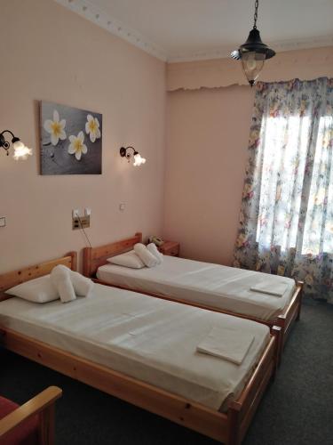 two twin beds in a room with a window at Hotel Faraggi in Kleidonia