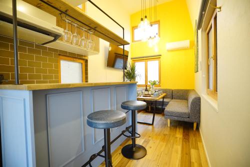 a bar with stools in a room with yellow walls at 貸切一軒家 東京ヴィラ リバーサイド平井 in Tokyo
