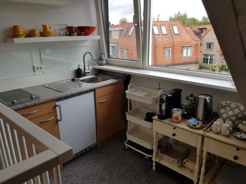 een kleine keuken met een wastafel en een raam bij Deluxe STUDIO-appartement Heemstede Zandvoort in Heemstede