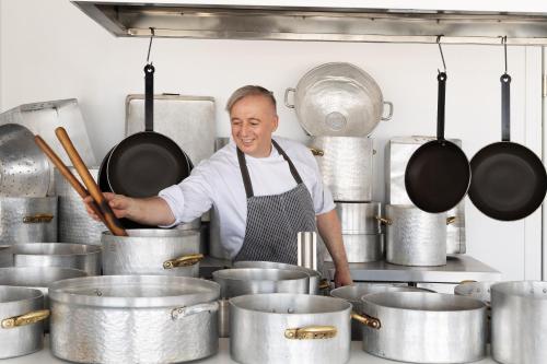 a man in a kitchen with pots and pans at Olympios Zeus in Plaka Litochorou