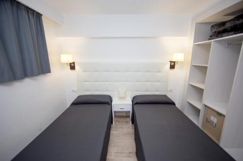 a room with two beds and a table and shelves at Pierre&Vacances Mallorca Portofino in Santa Ponsa