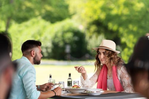 a woman in a hat sitting at a table eating food at Olympios Zeus in Plaka Litochorou