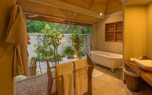 a bathroom with a tub and a large window at Denis Private Island Seychelles in Denis Island