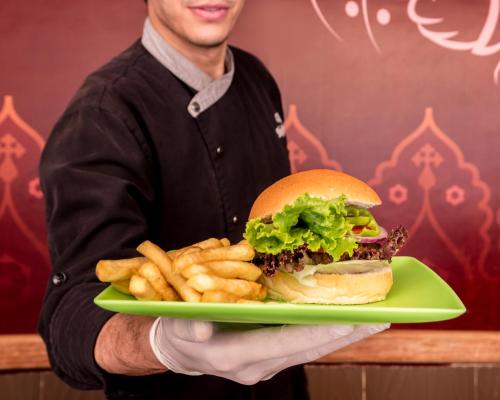 a man holding a plate with a hamburger and french fries at Serenity Alma Heights - Ex Serenity Fun City in Hurghada