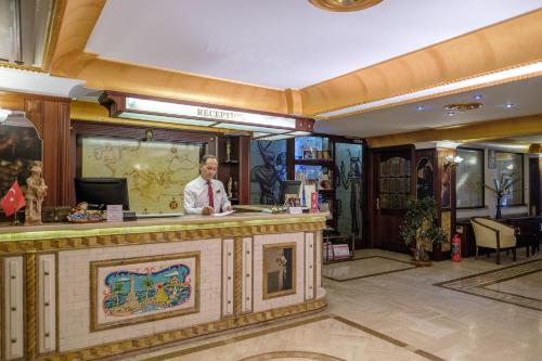 a man standing at a bar in a hotel lobby at Oğlakcıoğlu Park Otel in Izmir
