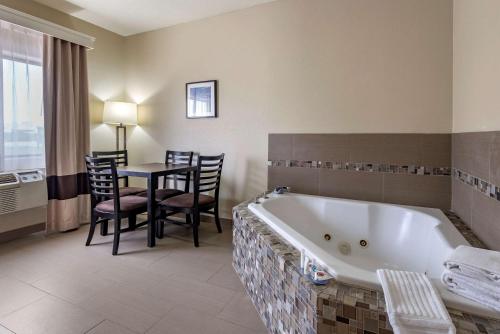 a bathroom with a tub and a table with chairs at Comfort Inn & Suites in Fruita
