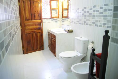a bathroom with a toilet and a sink and a door at Luciano & Grace Apartments in Watamu