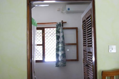 a room with a window and a door with a curtain at Luciano & Grace Apartments in Watamu