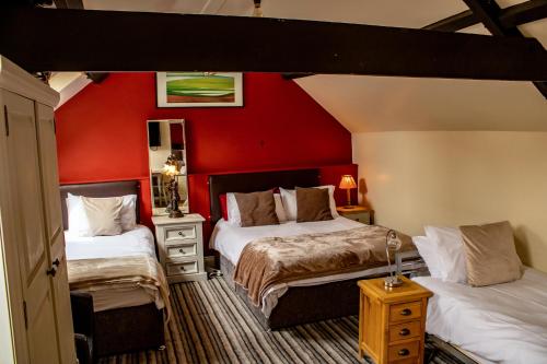 a bedroom with two beds and a red wall at The Dolphin Hotel in Chard