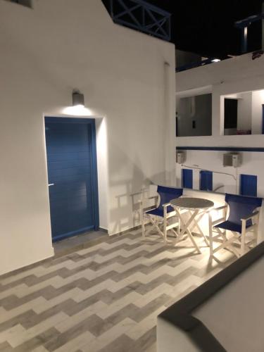 a room with a table and chairs and a blue door at Honeymoon Beach Studios in Perivolos
