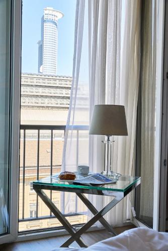 a glass table with a lamp in front of a window at Hotel Monopol - Central Station in Frankfurt/Main