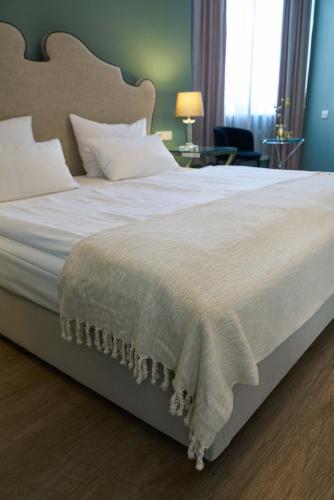 a bedroom with a large bed with white sheets and pillows at Hotel Monopol - Central Station in Frankfurt/Main