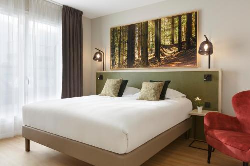 a bedroom with a large bed and a red chair at Citadines Eurometropole Strasbourg in Strasbourg