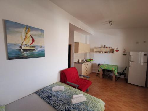 a room with a bed and a red chair and a kitchen at Apartments Montenegrina in Ulcinj