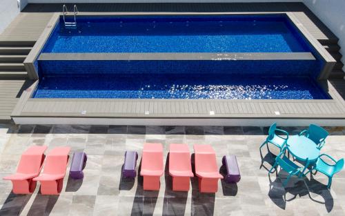 a pool with pink and blue chairs next to a swimming pool at Ibis Styles Balneário Camboriú - 1 Quadra do Mar in Balneário Camboriú