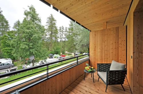 a wooden balcony with a chair and a large window at Ferienparadies Natterer See in Innsbruck