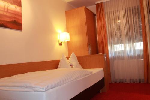 a bedroom with a bed with white sheets and a window at Hotel Hübler in Frankfurt/Main