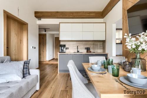 a kitchen and living room with a wooden table at Tatra Resort & SPA in Kościelisko
