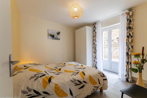 1 dormitorio con cama con edredón y ventana en Le Gîte de Mélie, en Pommard