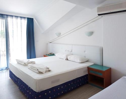 a bedroom with a large bed with white sheets and pillows at Navy Hotel in Marmaris