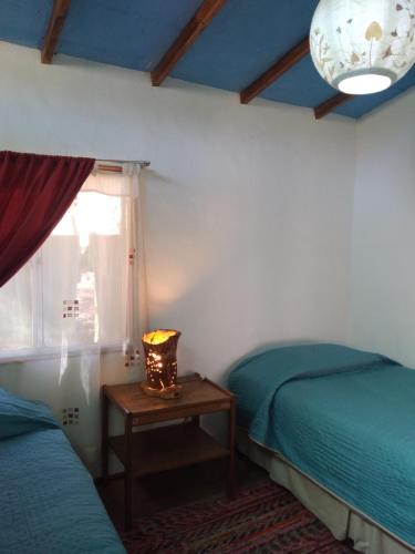 1 dormitorio con 2 camas y mesa con lámpara en Cabaña Canto del Viento, 4 personas, en Horcón