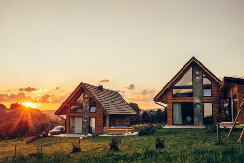 a house on a hill with the sunset in the background at The View House Rabka-Zdrój WELLNESS & SPA in Rabka