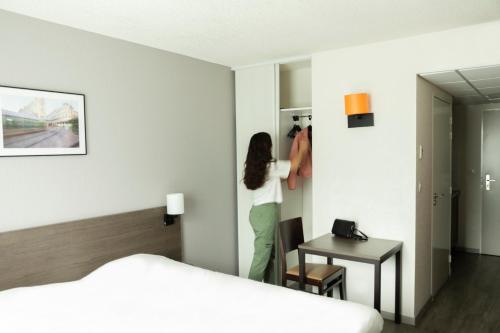 a woman standing in a hotel room looking in the mirror at Aparthotel Adagio Access Orléans in Orléans