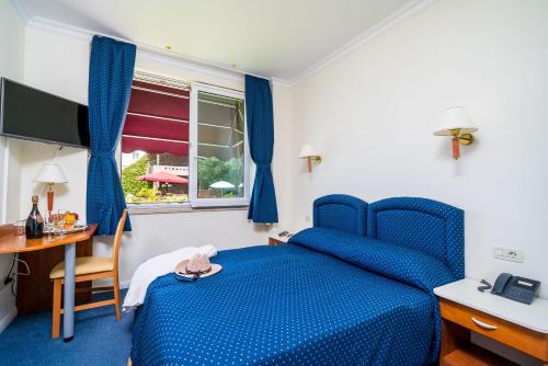 Boutique & Beach Hotel Villa Wolff في دوبروفنيك: غرفة نوم بسرير ازرق ومكتب ونافذة