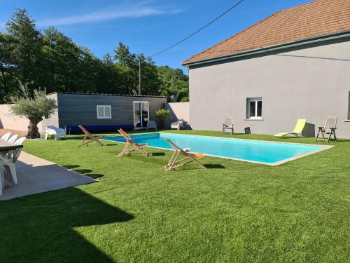 - une piscine dans une cour avec des chaises et une maison dans l'établissement Gîte des Vernizeaux, au Creusot