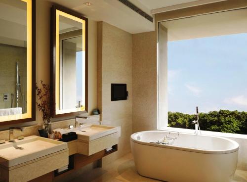 baño con 2 lavabos, bañera y ventana en The Oberoi Gurgaon, en Gurgaon