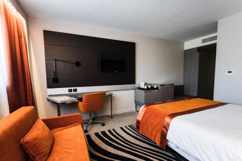 a hotel room with a bed and a desk and a tv at Novotel Orléans Saint Jean de Braye in Saint-Jean-de-Braye