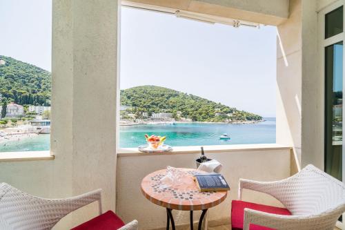 a room with a table and chairs and a view of the ocean at Boutique & Beach Hotel Villa Wolff in Dubrovnik
