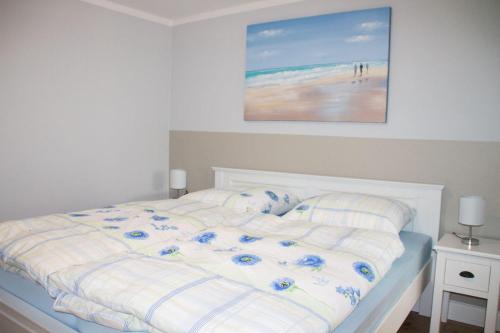 een slaapkamer met een bed met een schilderij aan de muur bij Haus-Holstein-Nr-5-App-3 in Westerland