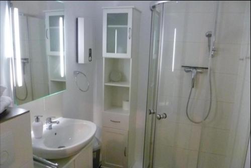 een witte badkamer met een douche en een wastafel bij Haus-Holstein-Nr-5-App-3 in Westerland