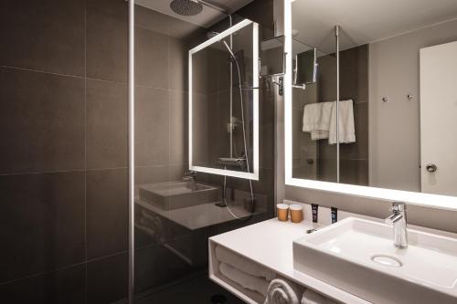 a bathroom with a sink and a shower and a mirror at Novotel Orléans Saint Jean de Braye in Saint-Jean-de-Braye