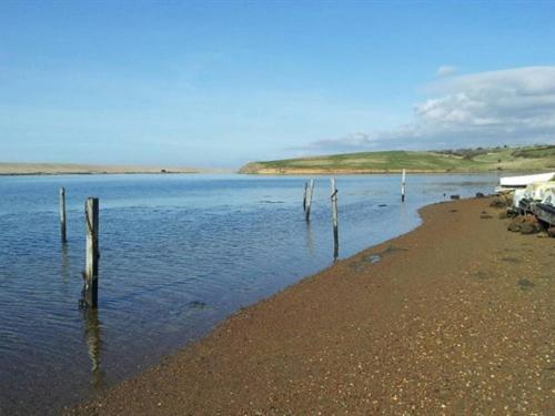 une plage avec des poteaux en bois accrochés à l'eau dans l'établissement Jurassic Apartments, à Weymouth