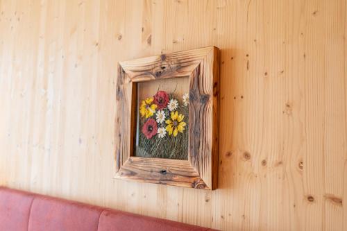 a picture of flowers in a wooden frame on a wall at Hotel Almschlössl & Schrotteralm in Obertauern