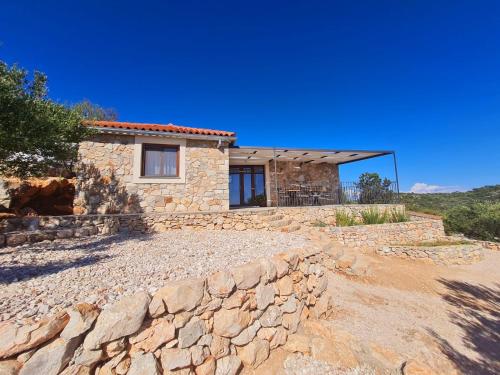 una casa in pietra con un muro di pietra di fronte di Luxury stone house in a Nature park a Sali (Sale)