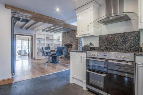 a kitchen with white cabinets and a stove top oven at Sea View - 2 Bedroom Cottage - Wisemans Bridge - Saundersfoot in Stepaside