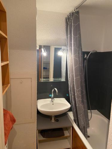 a bathroom with a sink and a shower curtain at Les pistes, studio 4 personnes au pied du télécabine in Oz