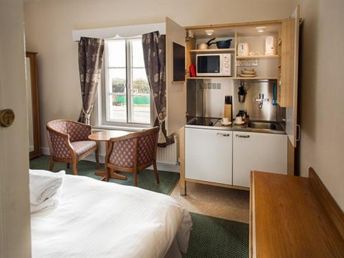 a room with a bed and a kitchen and a table at Albert & Victoria Hotel in Southport