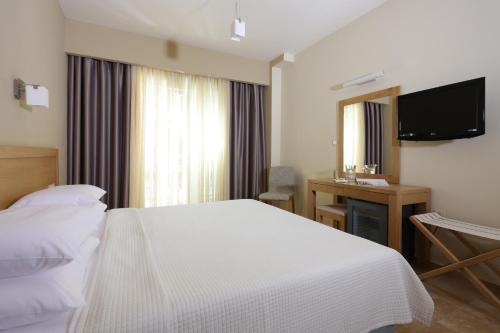 a bedroom with a bed and a desk and a television at Almira Hotel in Arkoudi