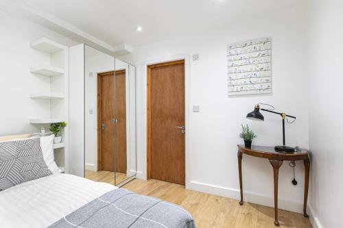 a bedroom with a bed and a wooden table at Skyvillion - One Bedroom Apartment by London King's Cross in London