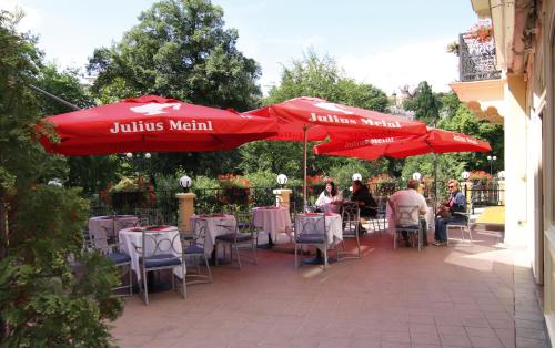 Un grupo de personas sentadas en mesas bajo sombrillas rojas. en Hotel Pavlov, en Karlovy Vary