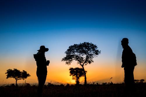 three people standing in a field at sunset at Umkumbe Safari Lodge Riverside in Skukuza