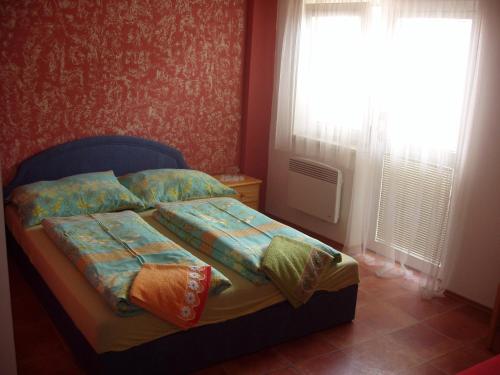 a bedroom with a bed with colorful pillows and a window at Penzion Orion Hovorany in Hovorany