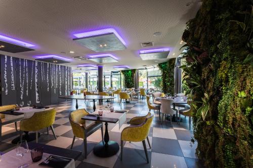 a restaurant with tables and chairs and a wall with plants at Novotel Orléans Saint Jean de Braye in Saint-Jean-de-Braye