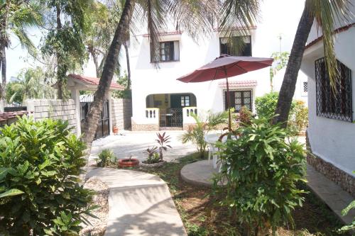 a patio with an umbrella and a house at Luciano & Grace Apartments in Watamu