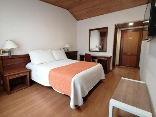 a bedroom with a bed and a table and a mirror at Daza Hotel in Paipa