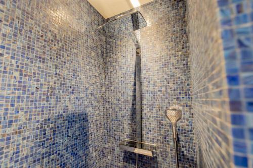 bagno con pareti piastrellate blu e doccia di Résidence Les Suites du Port ad Arcachon